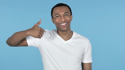 Smiling Man Giving a Thumbs Up on Blue Backdrop