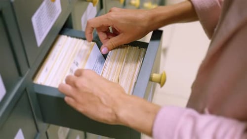 A Woman Hand Searching Cards in Old Wooden Card Catalogue