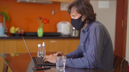 A Young Man Wearing a Face Mask Works From Home During Coronavirus Self-isolation. Slowmotion Shot