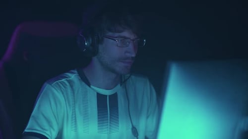 Young Man Using Computer with Headphones at Night