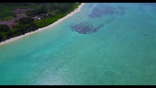 Un Zumbido aéreo tomó una panorámica de una idílica aventura en la playa junto al océano azul con fondo de arena blanca