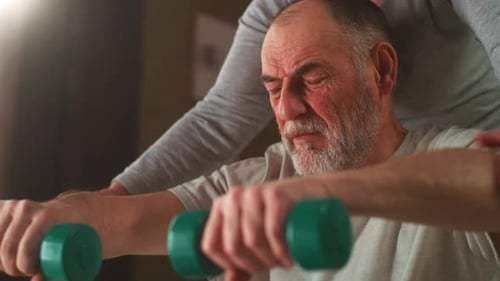 Senior Man Lifts Weights with Assistance at Home