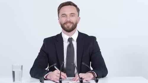 Man in Suit Writing at Press Conference