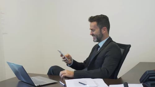 Man Working at Desk with Laptop and Smartphone