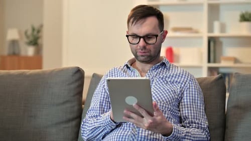 Excited Man Celebrates with Tablet on Couch