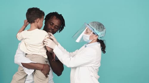 Doctor Gives Shot to Young Child Held by Dad