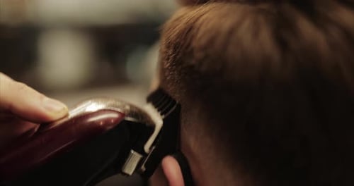 Der Barbier schneidet im Barbershop mit einer Haarschneidemaschine die Haare
