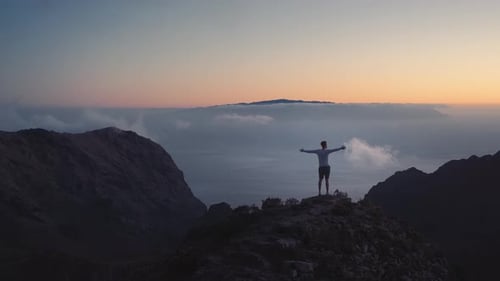 Lone Hiker on Mountain Peak at Sunrise