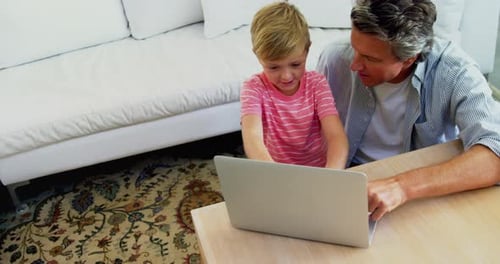 Child and Adult Working on Laptop Together