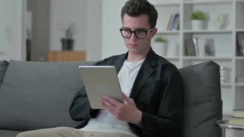 Young Man Using Tablet While Sitting on Couch