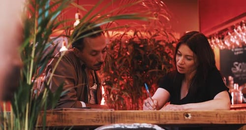 Woman and Man Discussing and Writing Together Indoors