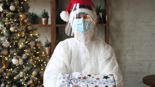 Person in Protective Suit Holds Christmas Gift