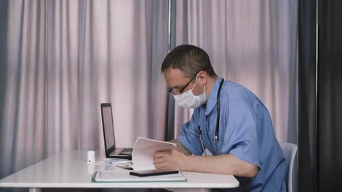 Male Doctor Working at Desk Frustrated