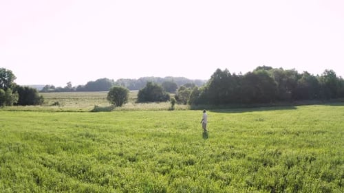 Farmer Walks on a Green Field