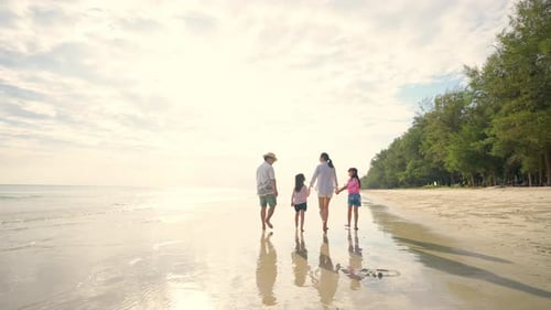 4K Asian family parents with two little daughter playing on the beach together at summer sunset.