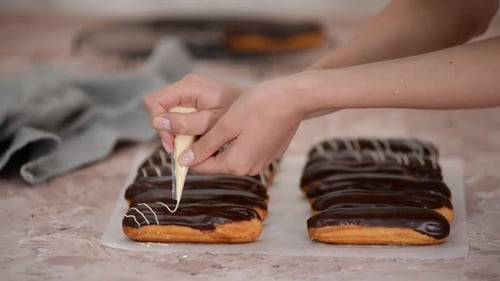 Woman Decorating Chocolate Eclairs with Frosting