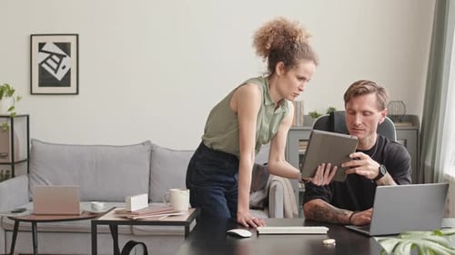 Woman Shows Man Tablet in Modern Office Setting