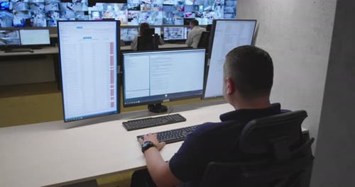 Man Monitors Multiple Screens in Security Control Room