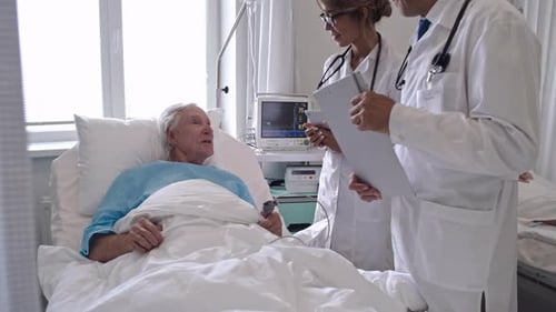 Practitioners Visiting Senior Man in Hospital Ward