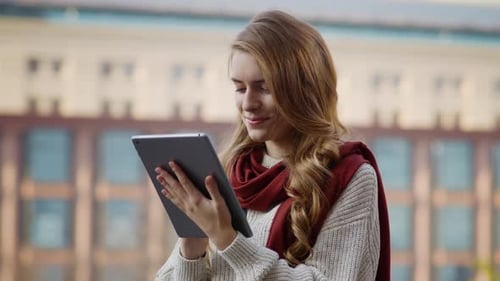 Pretty Woman Using Tablet Outdoors. Smiling Girl Touching Tablet on Street.