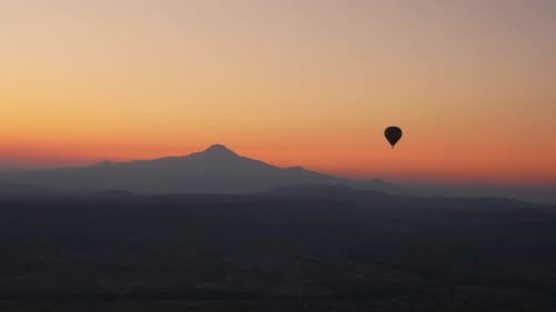 Hot Air Ballooning Over Mountain Range at Sunrise