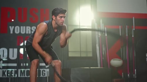 Active Caucasian athlete male or sportsman bodybuilder using battle Rope workout exercise in gym.