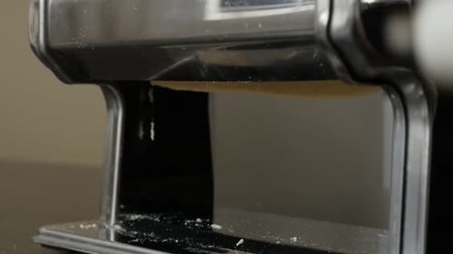 Pasta Dough being Rolled Through a Pasta Maker