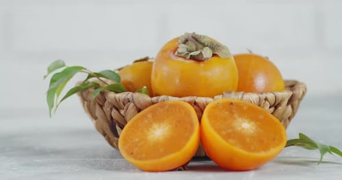 Frische Persimone im Korb mit Blättern rotiert langsam.