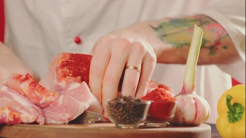 Chef Seasoning Meat With Spices on Cutting Board