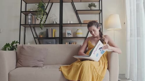 Pregnant Woman Reading Book in Living Room