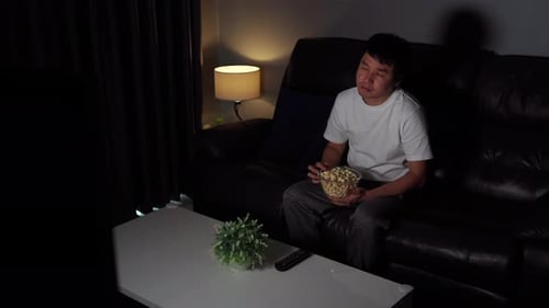 shocked young man watching TV movie on sofa at night