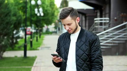 Modern Cheerful Man Uses the Phone on the Street