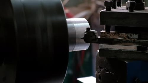 Worker handles aluminum metal piece on a lathe side view