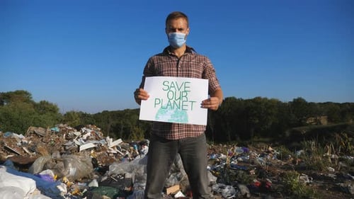 Man Holding Sign in Polluted Landfill Environment