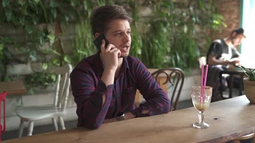 Young Man Talking on Phone Inside Cafe