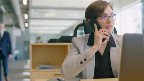 Businesswoman Talking on Phone at Desk in Office