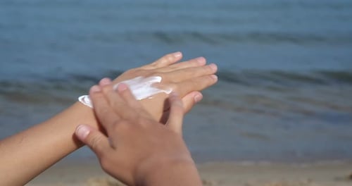Child Applying Sunscreen Lotion at the Beach