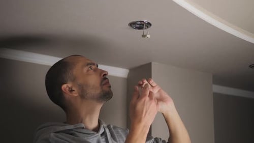 Man Installs New Ceiling Light Indoors
