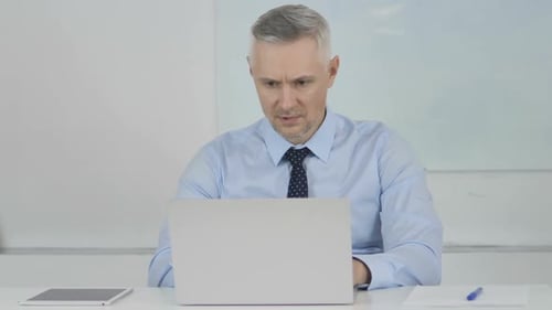 Serious Man Working at Laptop in Modern Office
