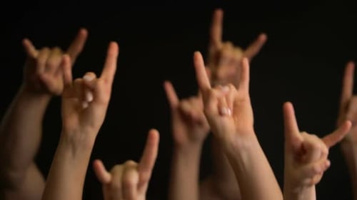 Raising Hands with Goat Gesture or Rock Sign on Black Background