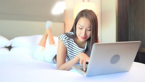 Woman Using Laptop Computer on Bed