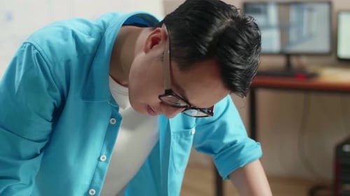 Close Up Of Asian Man Engineer With A Laptop Looking At Blueprint While Working At The Office