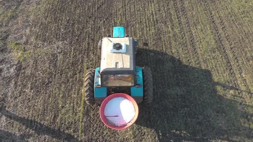Tractor Spreading Artificial Fertilizers in Green Field. Farmer Fertilizing Arable Land with