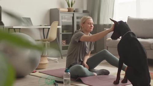 Woman Pets Doberman Dog on Exercise Mat