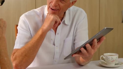Elderly Couple Discussing Tablet Information at Home