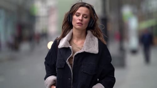 Pensive Lady Is Walking at City at Autumn Day, Listening Favorite Song in Headphones, Portrait