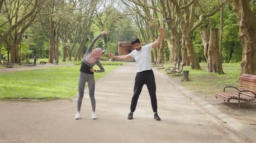 Active Woman in Sport Clothes and Hijab Stretching Legs at Summer Park