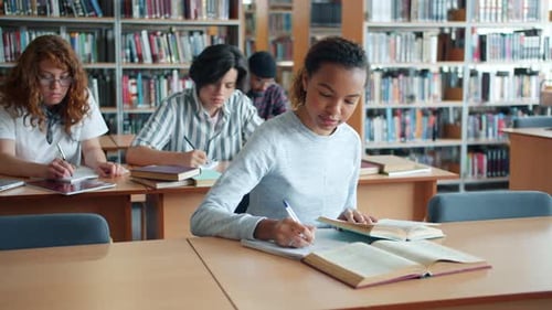 Slow Motion of Pretty Mixed Race Girl Studying in Library with Group of People
