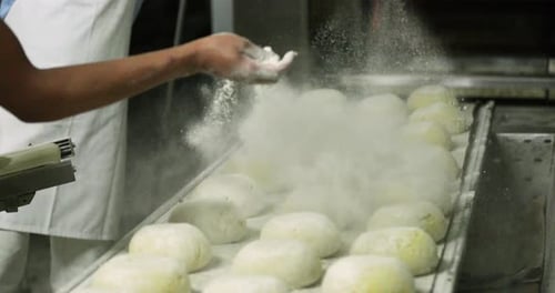 Sprinkling Flour on Dough Balls in Factory