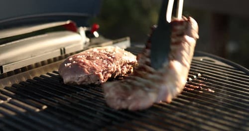 Man roasted meat on the gas grill on barbecue grill outdoor in the backyard